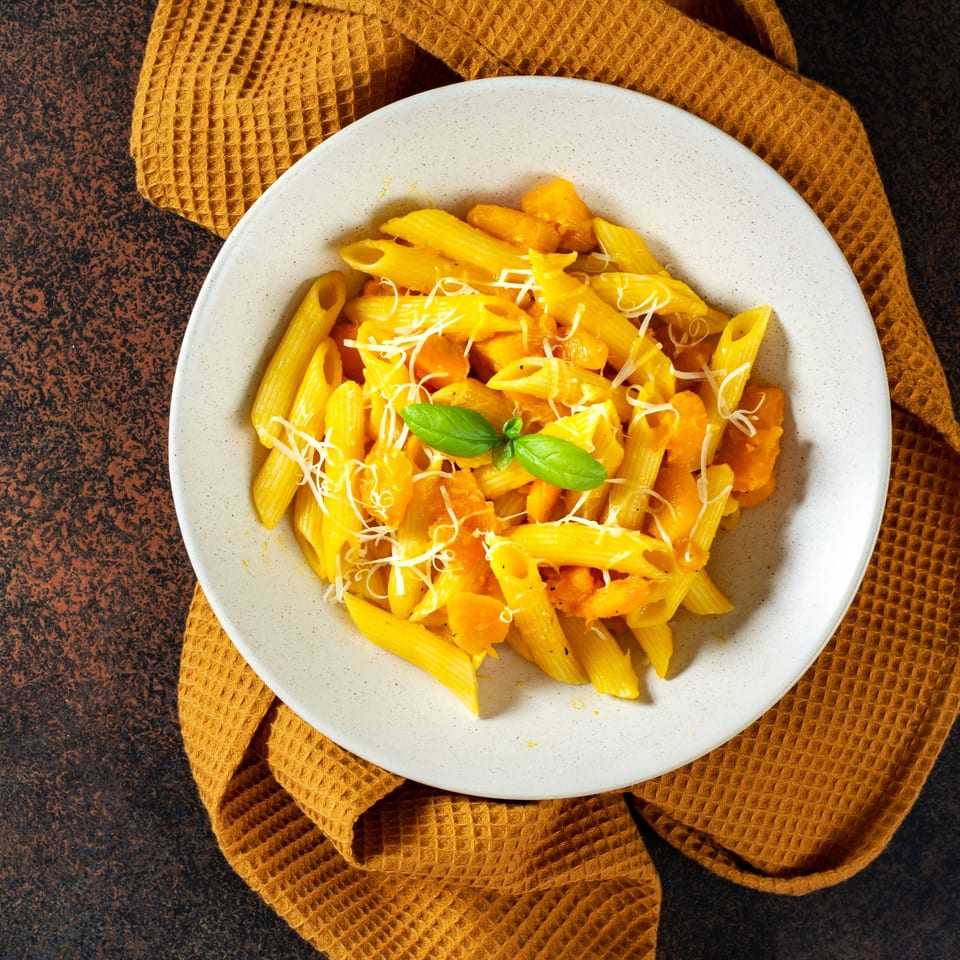 Celeno's Bistro's penne pasta with orange sauce, shredded cheese, and a basil garnish.